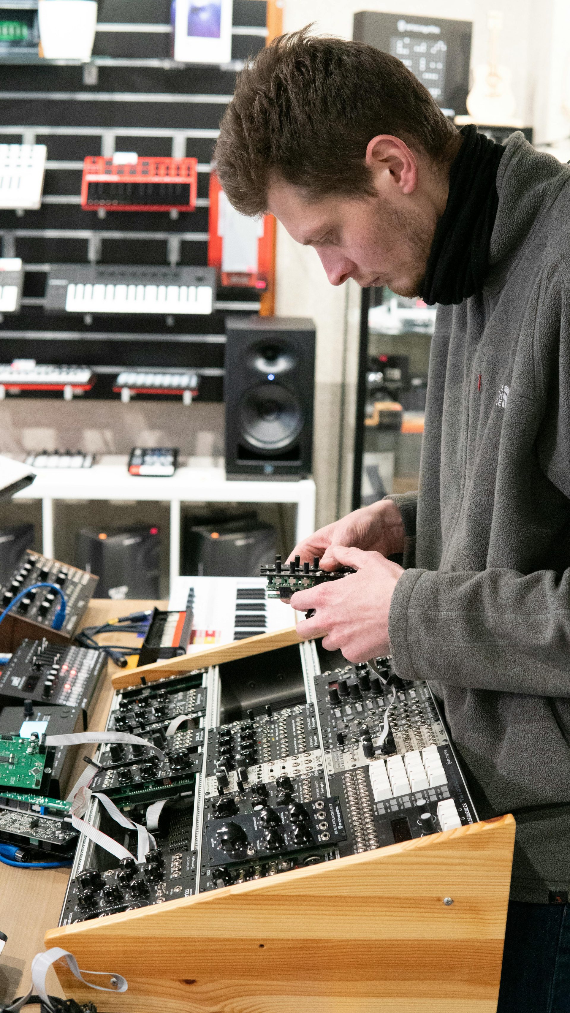 Un homme adulte assemblant des synthétiseurs modulaires dans un magasin d'électronique.