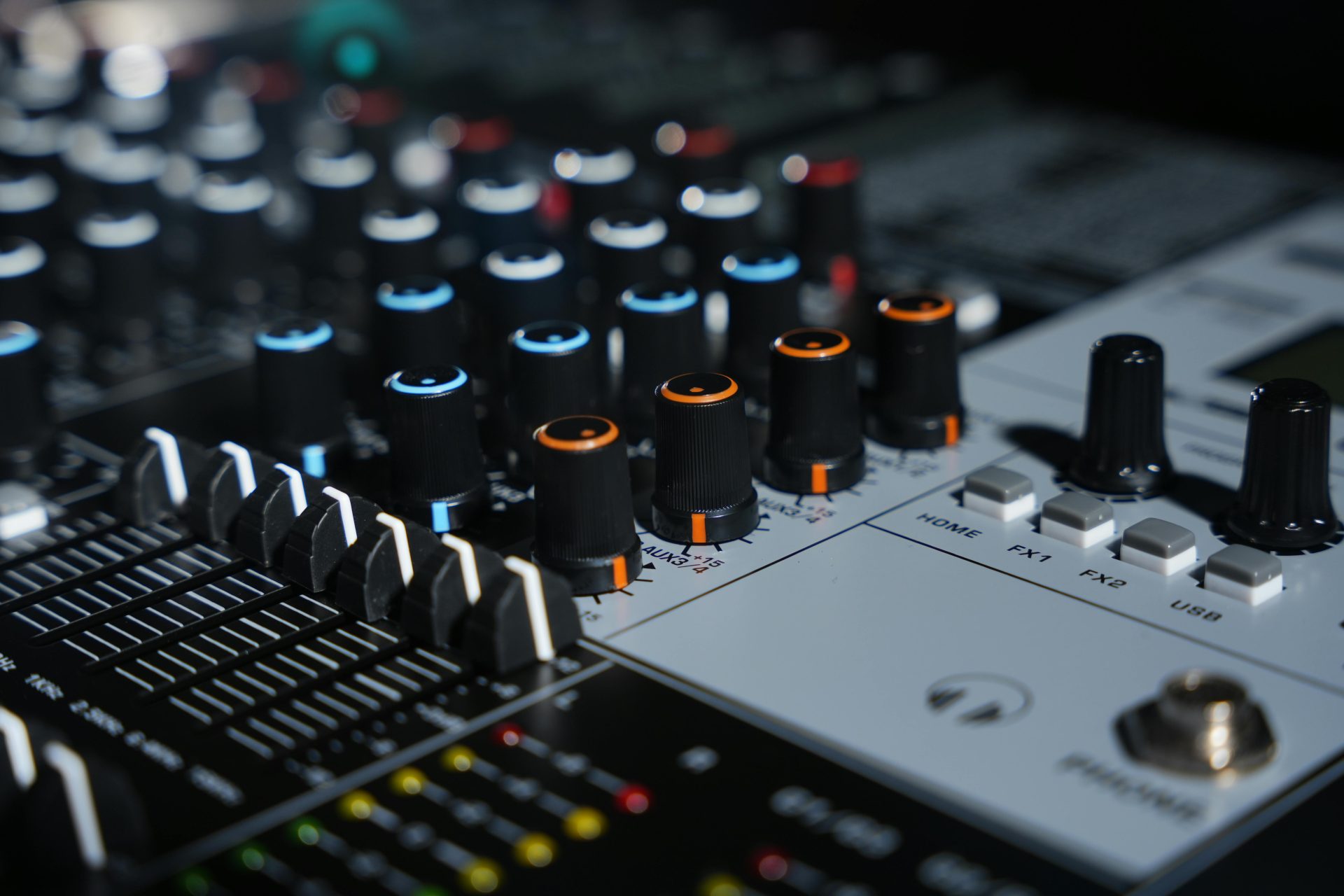 Gros plan sur une console de mixage moderne dans un studio d'enregistrement musical, avec un ingénieur du son en arrière-plan.